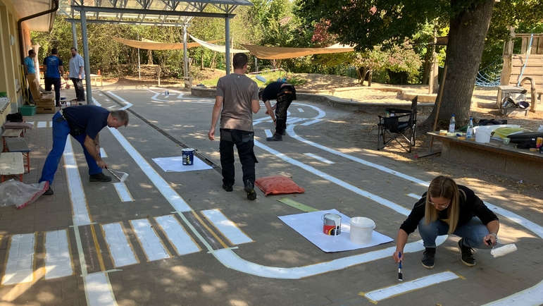 Freiwillige Helfer und Helferinnen arbeiten im Garten einer Kindertagesstätte in Deutschland.