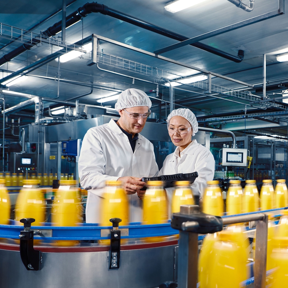 Arbeitskräfte stehen vor einer Produktionsanlage für Lebensmittel und Getränke