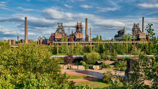 Stahlwerk inmitten einer grünen Landschaft.